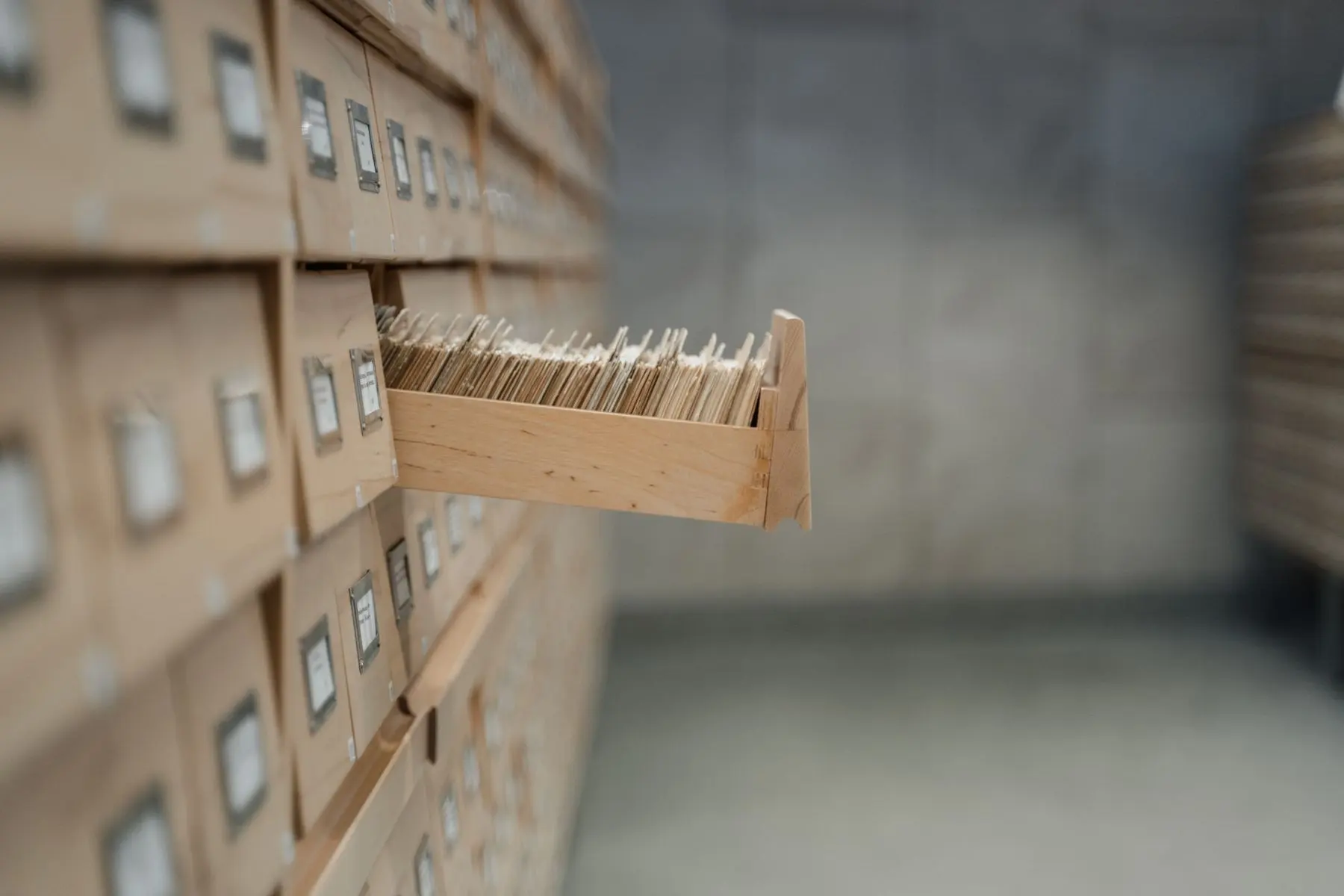 A wooden card catalog drawer pulled open, full of index cards